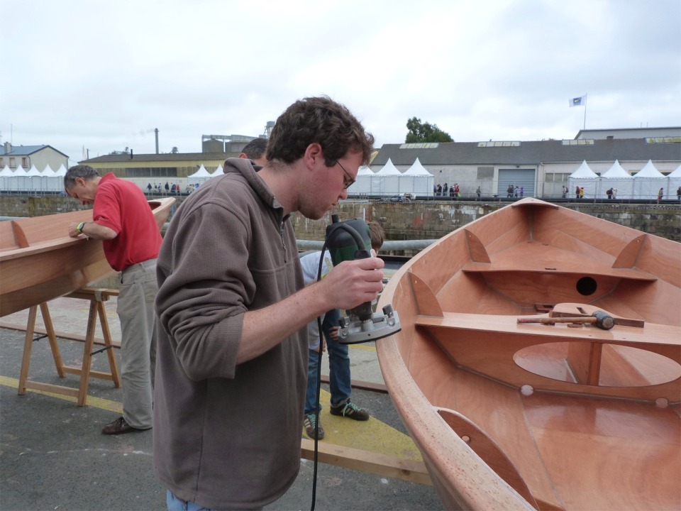 Erwan passe la défonceuse avec la fraise en quart de rond sur le bord des listons. 