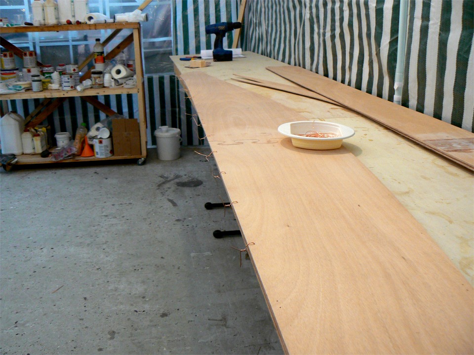 Les deux panneaux de fond sont sutur&eacute;s le long de la quille avec des petits bouts de fil de cuivre fourni dans le kit. Le c&ocirc;t&eacute; stratifi&eacute; est &agrave; l'int&eacute;rieur. L'ext&eacute;rieur sera stratifi&eacute; quand le kayak sera enti&egrave;rement construit. A droite de l'image, on voit les panneaux lat&eacute;raux, dont le joint puzzle n'est renforc&eacute; que par la bande de tissu de verre. La stratification int&eacute;rieure n'est pas n&eacute;cessaire sur ces panneaux, sur lesquels les contraites sont nettement moins importantes. 