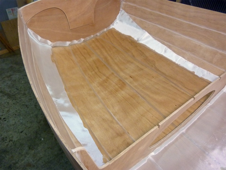 J'ai satur&eacute; le tissu de verre de l'arri&egrave;re sur les quatre bord&eacute;s de fond, et je couperai ensuite l'exc&eacute;dent de tissu, qui apparait encore en blanc sur cette image. En effet, la r&eacute;sine &eacute;poxy rend le tissu de verre transparent en le mouillant. Dans le bateau fini et verni, on ne distinguera que difficiliment la pr&eacute;sence de ce tissu. 