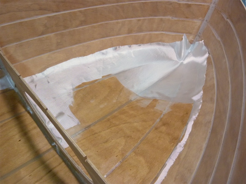 Je verse la r&eacute;sine &eacute;poxy sur le tissu de verre, puis je l'&eacute;tale et la fais p&eacute;n&eacute;trer dans la trame du tissu &agrave; l'aide de la "squeegee". J'ai enlev&eacute; la bande de renfort de l'&eacute;trave pour saturer la pi&egrave;ce principale, je m'en occuperai juste apr&egrave;s. 