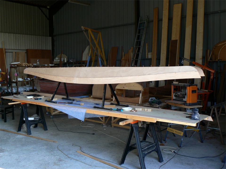 Je passe au montage du Sassafras 16. D&egrave;s que les bord&eacute;s 1 sont sutur&eacute;s sur la ligne de quille, je les juche sur des servantes &agrave; rouleau mont&eacute;es sur la table. Les rouleaux supportent la future coque le long de la suture de quille, et le tout est &agrave; une hauteur de travail confortable. Ici, le bord&eacute; 2 est sutur&eacute;. On constate sur cette image que la coque du Sassafras est strictement amphidrome. 