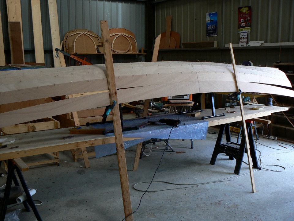 D&eacute;but de suture du bord&eacute; 5 : je commence par le milieu, en progressant alternativement vers chaque extr&eacute;mit&eacute;. Les b&eacute;quilles tiennent le bord&eacute; et la coque, de laquelle il est d&eacute;j&agrave; solidaire. 