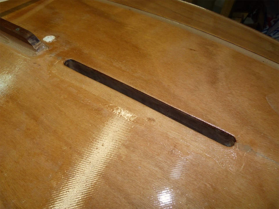 J'ai stratifi&eacute; une bande de fibre de verre de 5 cm de large sur tout le pourtour de l'ouverture du puits de d&eacute;rive afin de renforcer l'ar&ecirc;te. On aper&ccedil;oit &agrave; l'arri&egrave;re-plan &agrave; gauche le nable en plastique blanc que je viens de coller. Ce nable permettra d'&eacute;vacuer l'eau de pluie qui tomberait dans le Youyou lorsqu'il sera suspendu dans ses bossoirs, par exemple. 