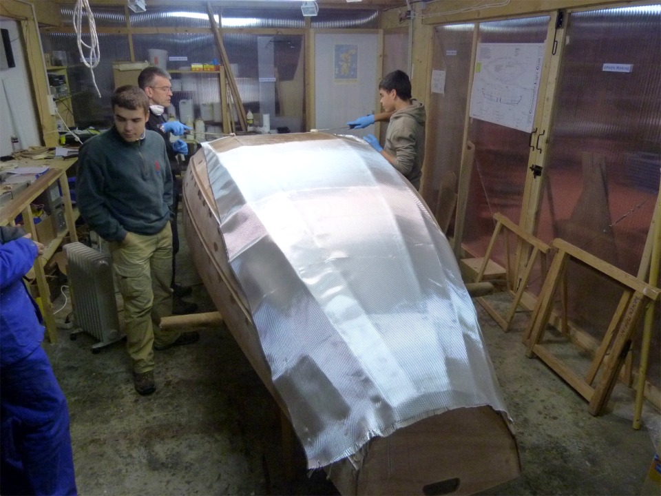 Cette fois-ci, nous utilisons des rouleaux pour saturer le tissu de verre d'&eacute;poxy, contrairement &agrave; l'int&eacute;rieur, o&ugrave; nous avons utilis&eacute; la squeegee. Le rouleau est int&eacute;ressant sur les surfaces convexes, car la r&eacute;sine coule et si on n'est pas vif comme l'&eacute;clair, on a rapidement les chaussettes qui collent ! L'inconv&eacute;nient du rouleau (outre le prix des manchons) est qu'il adh&egrave;re un peu au tissu qu'il a tendance &agrave; d&eacute;placer. C'est un monde impitoyable... 
