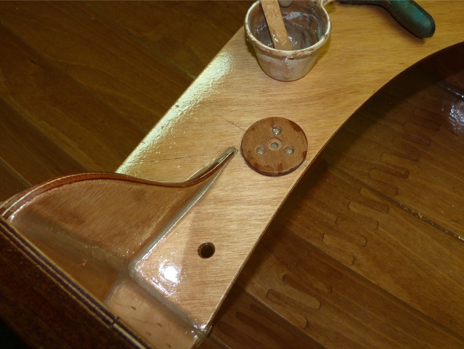 Collage des pastilles sur l'avant du si&egrave;ge central, ici c'est la pastille tribord. Nous la presserons avec la pince dont on aper&ccedil;oit un morceau en haut de l'image, car nous allons retourner la coque pour sa derni&egrave;re couche d'&eacute;poxy sur l'ext&eacute;rieur. 