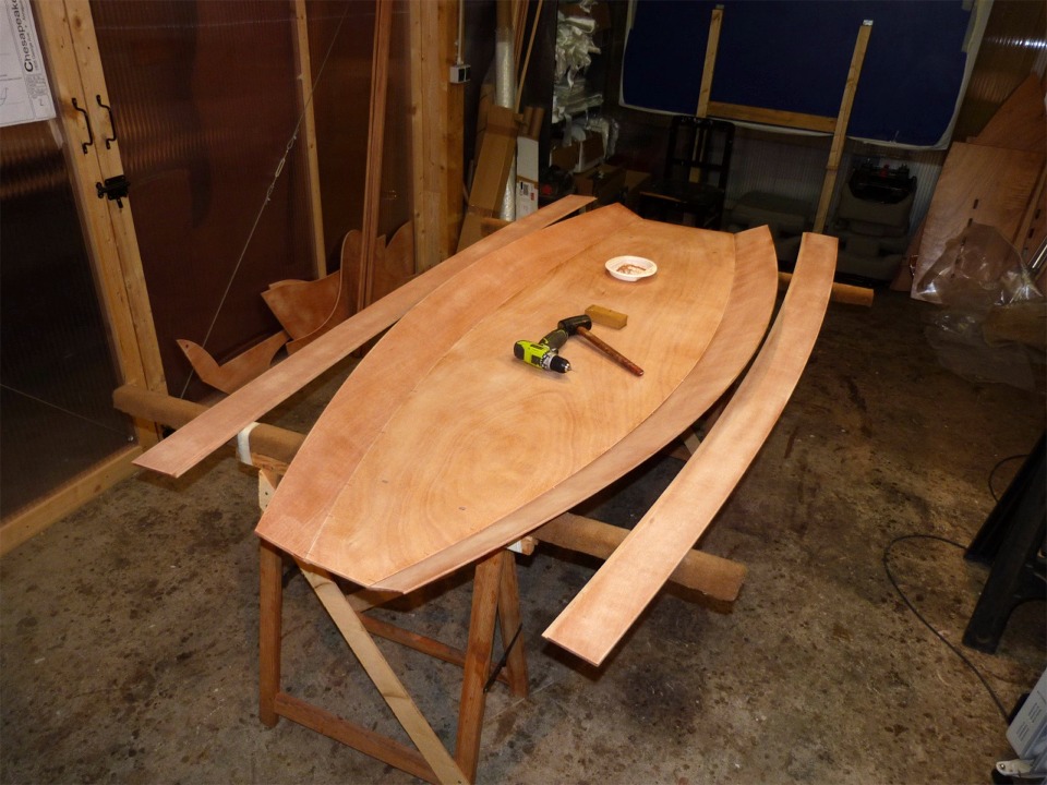 Les deux bord&eacute;s 1 sont sutur&eacute;s sur les bords de la sole et je m'appr&ecirc;te &agrave; suturer les bord&eacute;s 2, que j'ai d&eacute;ja pos&eacute;s sur mes tr&eacute;teaux &eacute;largis. Le pr&eacute;sence de la perceuse s'explique par le fait que j'ai partiellement bouch&eacute; les trous des sutures en passant ma couche d'impr&eacute;gnation. Le maillet sert &agrave; tapoter les extr&eacute;mit&eacute;s des bord&eacute;s afin de les positionner pr&eacute;cis&eacute;ment de niveau &agrave; l'avant. 