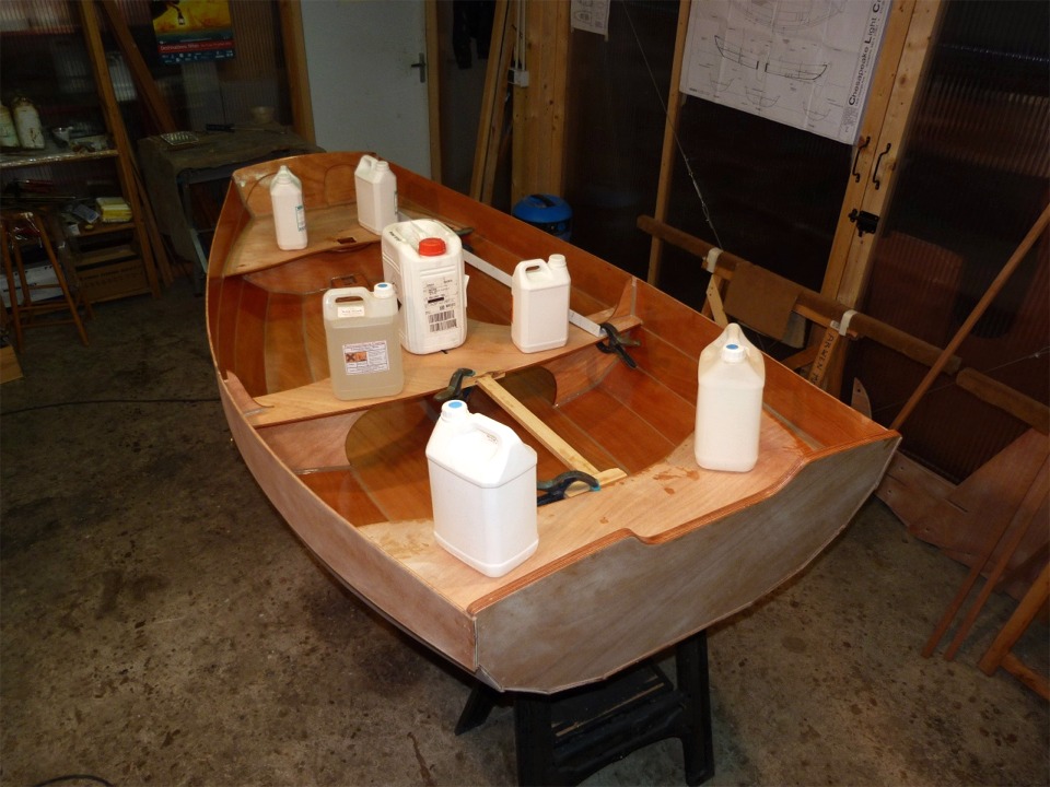 Apr&egrave;s avoir coll&eacute; le pied de m&acirc;t, j'ai pass&eacute; une nouvelle couche d'&eacute;poxy sur toute la surface int&eacute;rieure de la Prame d'Eastport, sur le dessous des si&egrave;ges, et j'ai coll&eacute; ceux-ci en place. Les bidons exercent un peu de pression sur les collages. Les tasseaux fix&eacute;s avec des pinces bloquent les si&egrave;ges avant et arri&egrave;re qui ont tendance &agrave; glisser vers le centre du bateau du fait de leur angle. Je ferai les joints-cong&eacute;s sous les si&egrave;ges ult&eacute;rieurement, un fois la coque retourn&eacute;e. 