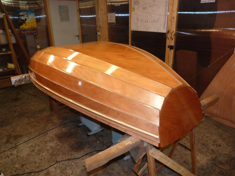 La seconde couche d'&eacute;poxy sur la partie stratifi&eacute;e &eacute;paissit la premi&egrave;re couche et "remplit la trame" du tissu de verre. Comme on le voit, j'ai &eacute;tendu cette seconde couche &agrave; toute la surface ext&eacute;rieure. Notez les radiateurs sous la coque : je l'ai chauff&eacute;e &agrave; fond (28&deg;C, il ne faut tout de m&ecirc;me pas r&ecirc;ver) avant de commencer la stratification et j'ai ensuite l&eacute;g&egrave;rement baiss&eacute; les radiateurs afin de maintenir la temp&eacute;rature pour que l'&eacute;poxy durcisse. 