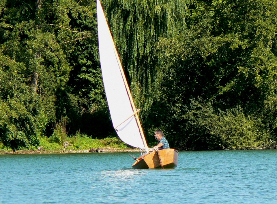 Ce type de carène plate à simple bouchain donne son maximum en la laissant gîter un peu. Sur cette image, j'ai été surpris par une risée et je mets presque le liston dans l'eau... On n'a pas la même augmentation progressive de stabilité latérale que sur le Skerry, dont la coque, plus fine à la flottaison, s'élargit très rapidement à la gite. 