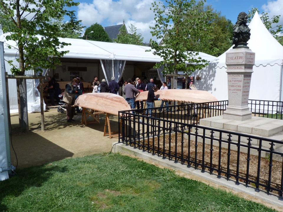 Puis nous sortons les deux coques pour passer au ponçage, qu'il serait asocial de faire à l'intérieur du chapiteau. On distingue un certain nombre de presses sur le liston du Skerry de droite : en effet, nous avons constaté que l'époxy du collage des listons n'avait pas assez durci pendant la nuit à cet endroit et nous avons donc réinjecté un peu d'époxy chargée et remis les presses sur une longueur de 2 m à peu près. 