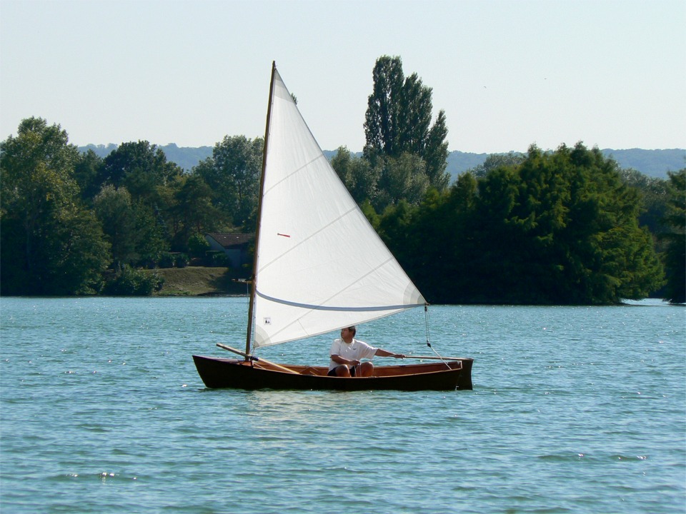 On voit bien ici l'ombre du balestron sur la voile, et sa hauteur par rapport à la tête du barreur : il faudra qu'il se lève pour risquer de se cogner la tête ! Le bout de réglage de tension du balestron revient sur l'arrière du puits de dérive, ainsi que le réglage de tension du guindant, à la main du barreur. 