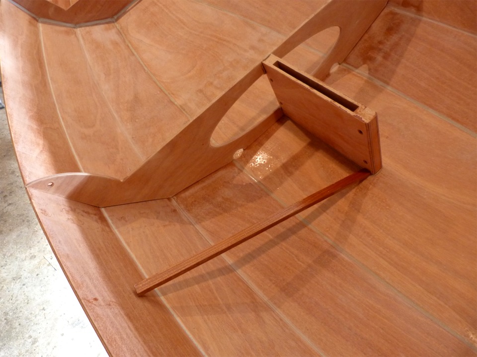 La baguette me permet de maintenir le puits de d&eacute;rive align&eacute; sur ses marques afin de visser les deux vis qui le tiennent &agrave; travers la sole. Il est d&eacute;ja tenu par une vis &agrave; travers la cloison et a tendance &agrave; pivoter dans le sens de la pente, car j'ai cal&eacute; le Skerry en position oblique afin de visser plus ais&eacute;ment par dessous la coque. 