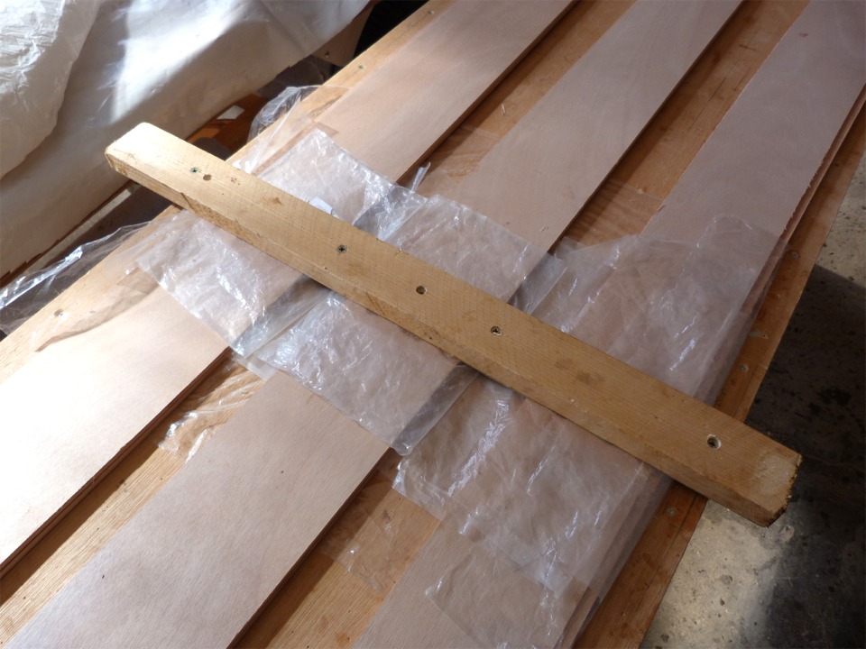 Apr&egrave;s encollage au pinceau de tous les chants des deux cot&eacute;s des joints, j'engage les joints, j'aligne soigneusement les paires de bord&eacute;s (&agrave; l'aide d'une pince &agrave; chaque ext&eacute;mit&eacute; de chaque paire) et je visse ce tasseau en travers des joints afin de les presser. Les feuilles de plastique &eacute;vitent de coller le tout ensemble... 