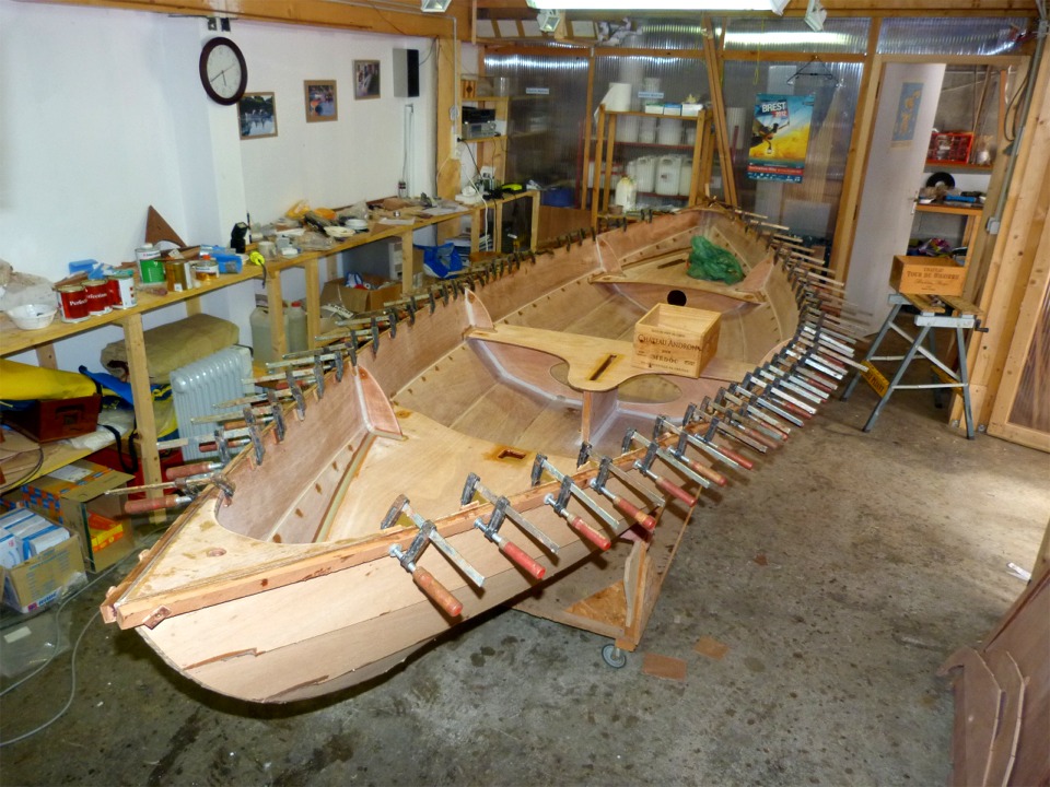 On aper&ccedil;oit ici les vis temporaires de l'avant : une seule sur b&acirc;bord et deux sur tribord, car une seule ne fermait pas assez le joint de collage sur la guirlande. Notez aussi les retouches d'&eacute;poxy sur l'int&eacute;rieur de la coque : j'ai notamment repass&eacute; un coup d'&eacute;poxy charg&eacute;e sur les trous des sutures, d&eacute;j&agrave; bouch&eacute;s, mais le bois avait "bu" l'&eacute;poxy et recr&eacute;&eacute; une concavit&eacute; sur les trous. J'ai aussi pass&eacute; un peu d'&eacute;poxy claire sur le pourtour de l'ouverture du puits de d&eacute;rive, de l'&eacute;tambrai et de tous les trous en t&ecirc;te des membrures. 