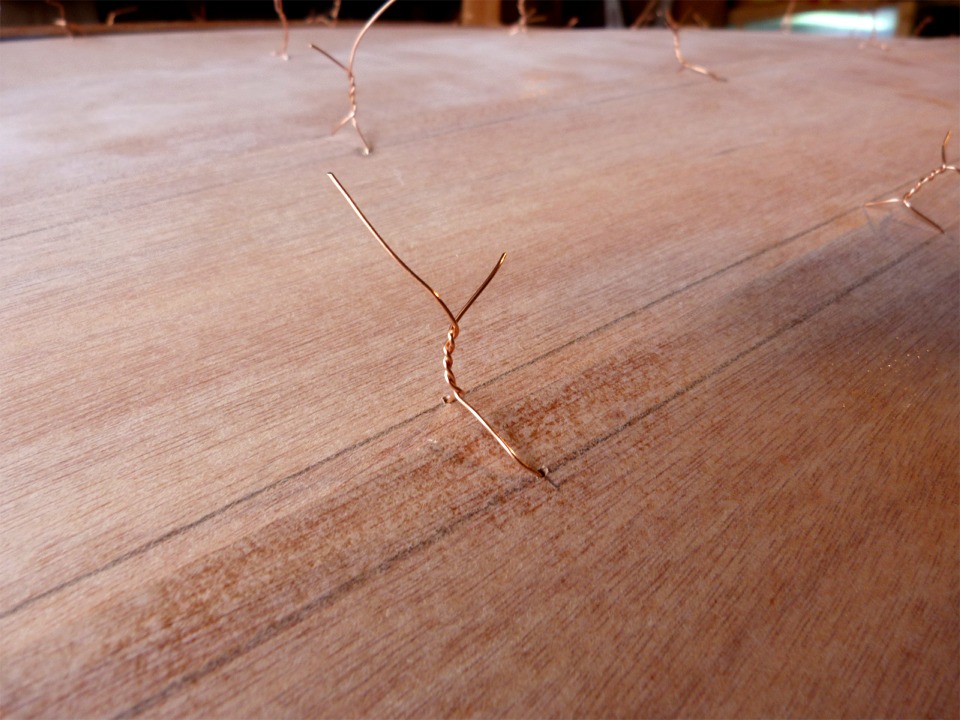 Gros plan sur une suture. Les lignes au crayon tracées le long des cotés des bordés permettent de positionner les trous au moment de leur percement. 