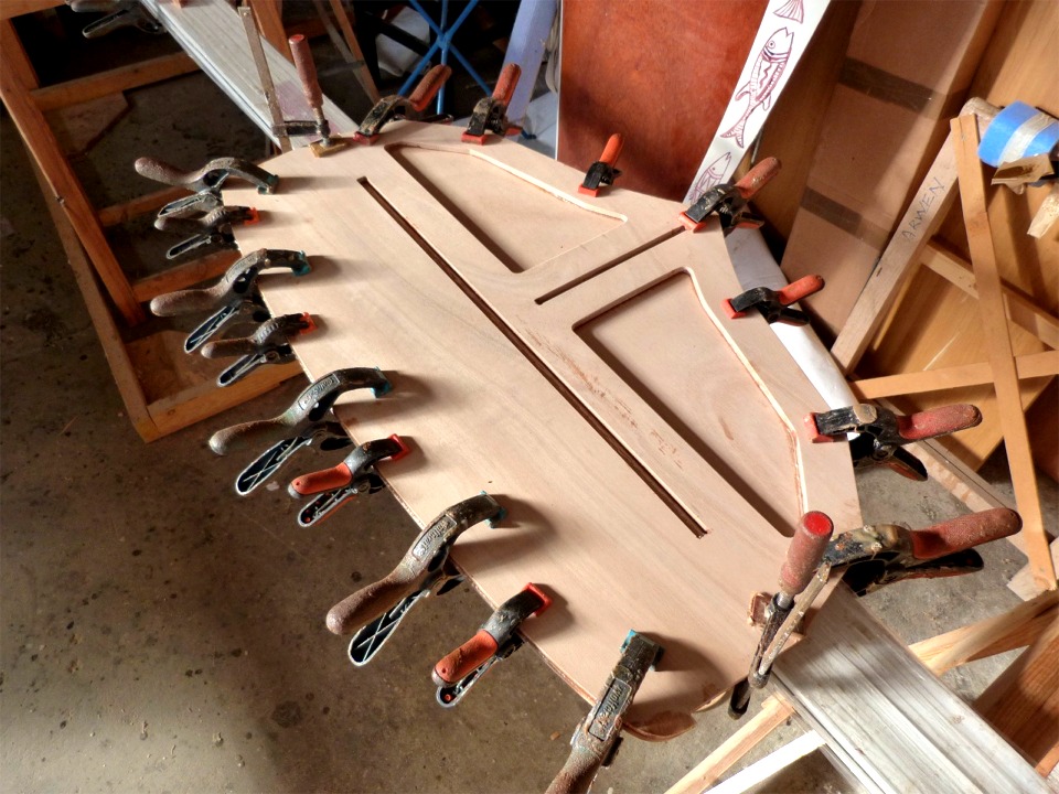 En parall&egrave;le, je colle le doubleur de tableau sur le tableau. Les rainures serviront de guides d'assemblage pour le pontage arri&egrave;re et pour l'&eacute;tambot. Les grandes d&eacute;coupes visent &agrave; all&eacute;ger cette pi&egrave;ce lourde. Il n'y a pas de trou de godille mais je pr&eacute;vois de fournir un gabarit afin que chacun la d&eacute;coupe o&ugrave; il le souhaite : au centre, sur b&acirc;bord, ou nulle-part. Je pense aussi faire une lumi&egrave;re pour le passage de la barre, ce qui permet de r&eacute;duire la hauteur (et le poids) du gouvernail. 