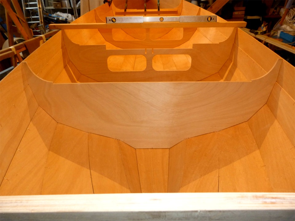 Vue vers l'avant depuis le haut du tableau arri&egrave;re. On voit tr&egrave;s bien l'amorce du retour de galbord dans le bas de la cloison 4. Le niveau &agrave; bulle me sert &agrave; v&eacute;rifier l'absence de vrillage dans la coque : je le prom&egrave;ne d'avant en arri&egrave;re en veillant &agrave; ce que le tasseau sur lequel il navigue reste perpendiculaire &agrave; l'axe du bateau. 