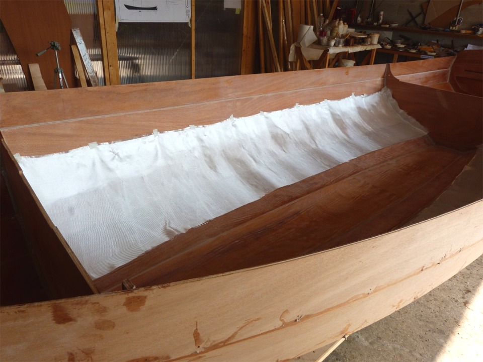 J'ai scotch&eacute; le haut du tissu afin qu'il tienne en place en attendant de le saturer de r&eacute;sine &eacute;poxy. J'ai pr&eacute;vu de remplacer ces deux grammages et ces trois pi&egrave;ces de tissu de verre par deux pi&egrave;ces de 200 grammes qui seront simplement crois&eacute;es sur la sole. L'ext&eacute;rieur de la coque sera stratifi&eacute; sur la m&ecirc;me zone que celle qui est couverte par le premier tissu &agrave; l'int&eacute;rieur : sole et 4 bord&eacute;s de fond. 