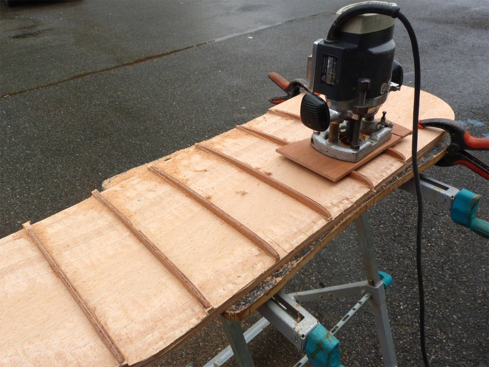 J'ai fix&eacute; un "patin" (une chutte de contreplaqu&eacute; de taille ad&eacute;quate) sous ma d&eacute;fonceuse et je la prom&egrave;ne sur les nervures profil&eacute;es que j'ai coll&eacute;es sur la d&eacute;rive. La fraise coupe &agrave; la fois en bout et sur les cot&eacute;s, et j'ai r&eacute;gl&eacute; sa profondeur pour affleurer la surface du contreplaqu&eacute; &agrave; l'endroit le plus haut des nervures. En d&eacute;pla&ccedil;ant la d&eacute;fonceuse sur les nervures, je reproduis leur contour sur la surface du contreplaqu&eacute;. La largeur du patin assure qu'elle repose sur deux nervures quel que soit l'endroit o&ugrave; je la prom&egrave;ne.