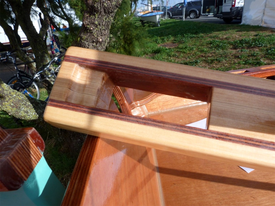 La mortaise &eacute;pouse sur le dessus et &agrave; l'arri&egrave;re la forme de l'ergot de la t&ecirc;te de gouvernail. Elle pr&eacute;sente un l&eacute;ger biais sur l'avant pour "coller" au mieux &agrave; la forme du tenon. Les deux &eacute;paisseurs de contreplaqu&eacute; makor&eacute; forment des couches dures qui &eacute;viteront les d&eacute;formations par &eacute;crasement. La barre doit encore &ecirc;tre renforc&eacute;e par des pi&egrave;ces traversantes en laiton de part et d'autre de la mortaise. 