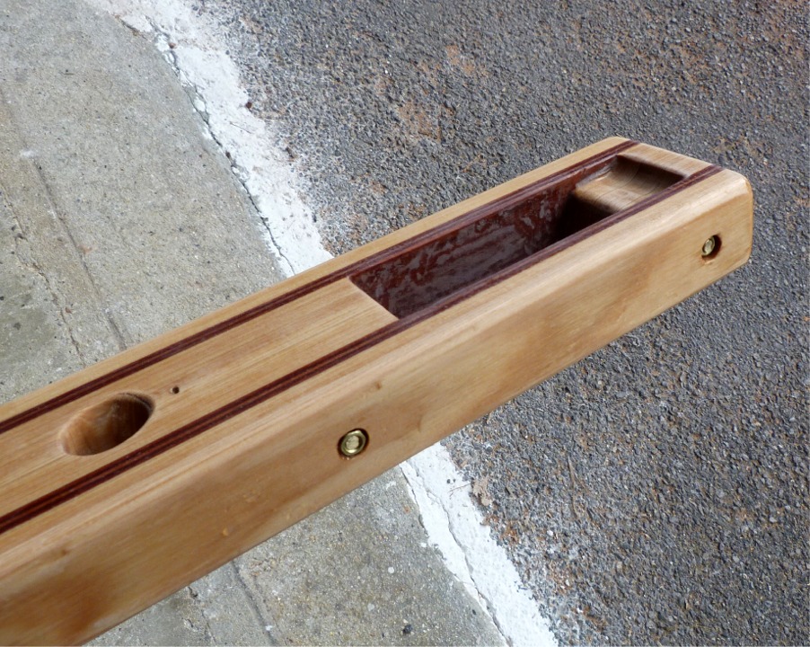 J'ai perc&eacute; la barre de part et d'autre de la mortaise qui vient se loger sur la t&ecirc;te de gouvernail et pos&eacute; des renforts traversants en tige filet&eacute;e de laiton, avec un &eacute;crou &agrave; chaque bout. Les &eacute;crous sont noy&eacute;s et seront ensuite coll&eacute;s &agrave; l'&eacute;poxy charg&eacute;e. Le gros trou rond &agrave; gauche sert &agrave; tenir le m&acirc;t de pavillon.