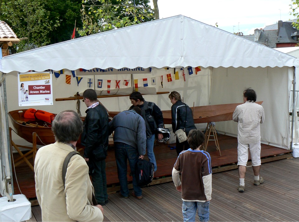 Et voici le stand Arwen Marine, sur la rive droite du bassin. J'ai déjà commencé à "coudre" le Doris 12. La première paire de bordés est à poste et je suis au travail sur le second bordé babord. Comme toujours, le vernis de la prame fait beaucoup d'admirateurs. 