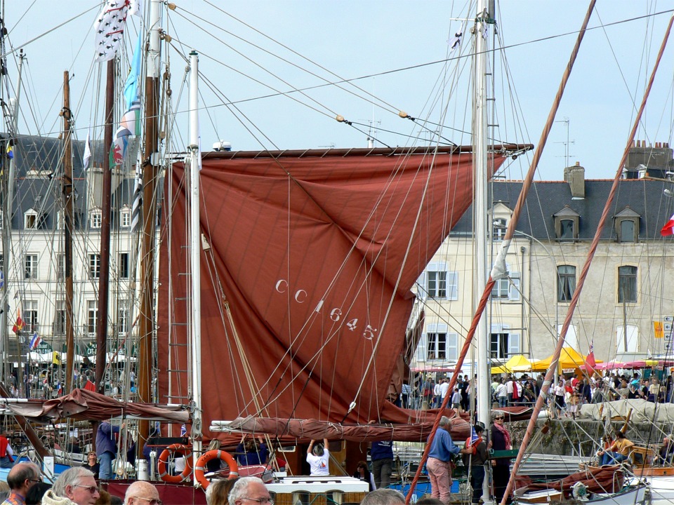 Samedi soir, c'est l'arrivée de la flottille "Voiliers de Travail". "Marche Avec", réplique de "Gaby", cotre-sardinier de 1924, est en train d'afaller sa grand-voile. Notez comme la double balancine de bôme sert de "lazy-jack" pour guider la corne. 