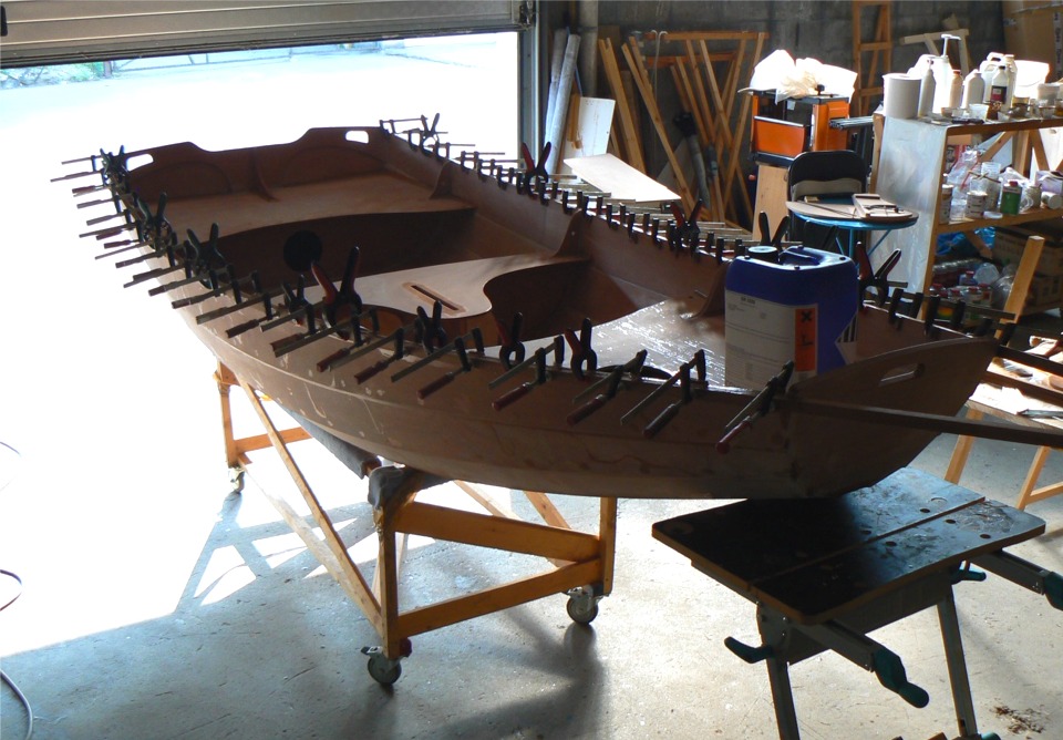 Je viens de coller le premier pli des listons. J'ai dispos&eacute; l'&eacute;tabli au premier plan &agrave; gauche sous la marotte pour soutenir la proue, surcharg&eacute;e par le bidon de r&eacute;sine qui assure la pression de collage pour les "caches-joints" pr&eacute;sent&eacute;s plus haut. 