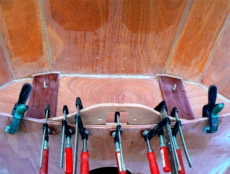 Voici le collage de l'étambrai, sous la "jupe" du dessus du caisson avant. On aperçoit les quatre trous des vis qui vont très prochainement me servir à fixer le pied de mât (qui sera aussi collé à l'époxy chargée, comme tout le reste du bateau). 