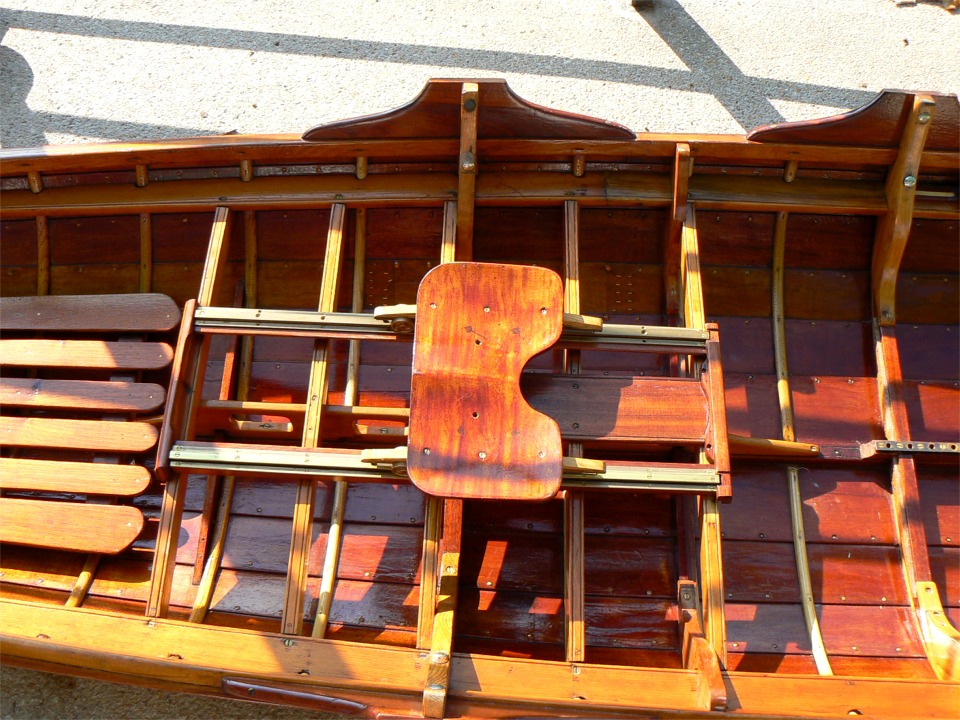 Curieusement, le si&egrave;ge de ce magnifique skiff classique est &agrave; l'envers. Les outriggers (il doit exister un mot fran&ccedil;ais...) se fixent &agrave; l'aide de vis papillon sur les sabots qui permettent de rehausser leur ancrage et donc de donner plus de hauteur &agrave; l'aviron par rapport aux genoux du nageur. 
