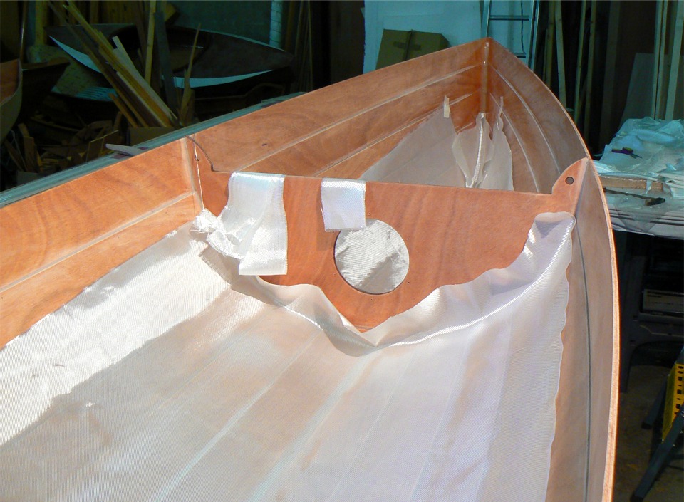 Et voilà les autres pièces de tissu en place. J'ai coupé un triangle pour compléter le rectangle du caisson avant, afin de limiter les plis dans l'étrave. Sur les parois verticales, le tissu tient grâce à des bouts d'adhésif, en attendant l'époxy. 