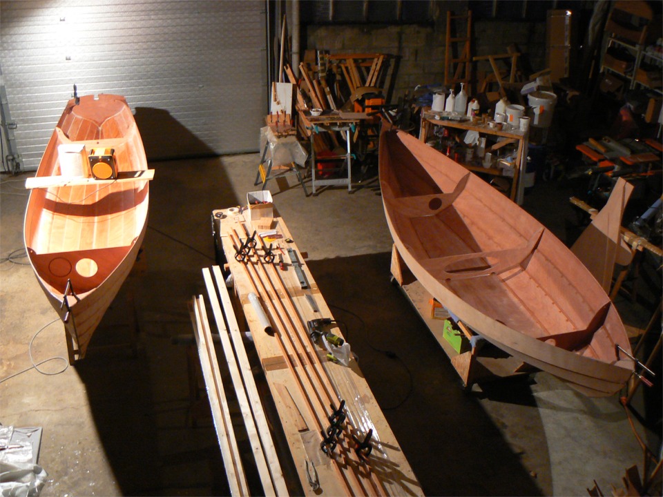 Vue des deux bateaux en construction. Sur la table au milieu, ce sont les listons du Skerry : ils comportent deux scarfs pour arriver à la bonne longueur (la longueur unitaire est limitée à 2.49 m par le carton du kit). A gauche de la table, je m'apprête à coller les espars du Skerry. 