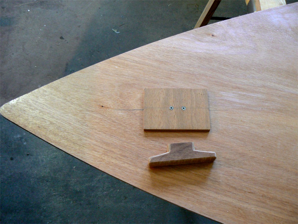 J'ai passé une couche d'imprégnation sur la face inférieure des dessus de caissons de la yole. J'en profite pour coller une contre-plaque pour visser-coller un taquet d'amarrage à l'avant. Le taquet est typique de la pièce que l'on taille dans une chute provenant du "trésor"... 