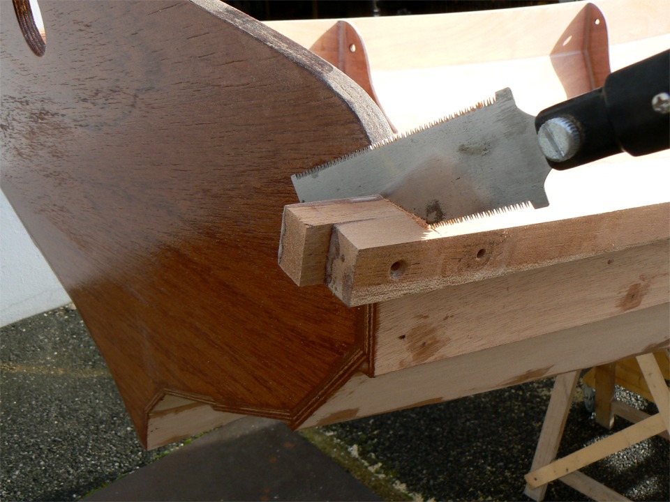 Je coupe les extr&eacute;mit&eacute;s des listons &agrave; l'aide d'une scie tr&egrave;s fine afin de ne pas endommager le tableau. Notez la diff&eacute;rence entre les deux trous de vis : celui de gauche a &eacute;t&eacute; frais&eacute; par la vis temporaire, alors que celui de droite ne l'est pas car la vis &eacute;tait munie d'une cale de protection. Je vais fraiser, remettre une vis inox et fermer par un tapon (ou tapet) d&eacute;coup&eacute; dans la chute que je suis en train de couper. 