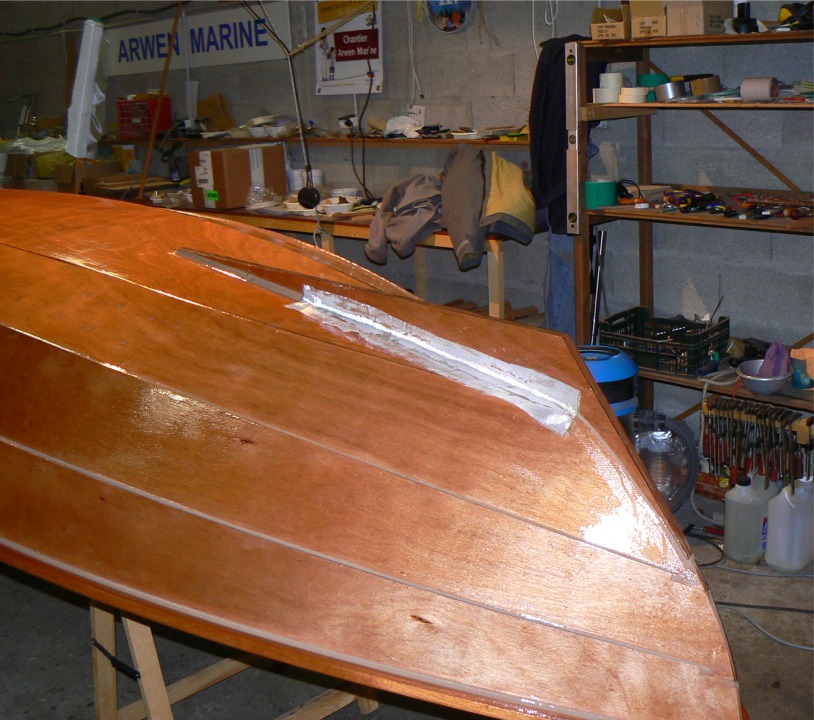 Je renforce le collage de l'aileron du Skerry par des bandes de fibre de verre, que je pose directement sur les joints "mouillés". Je sature ensuite la bande de fibre à l'époxy "claire". 