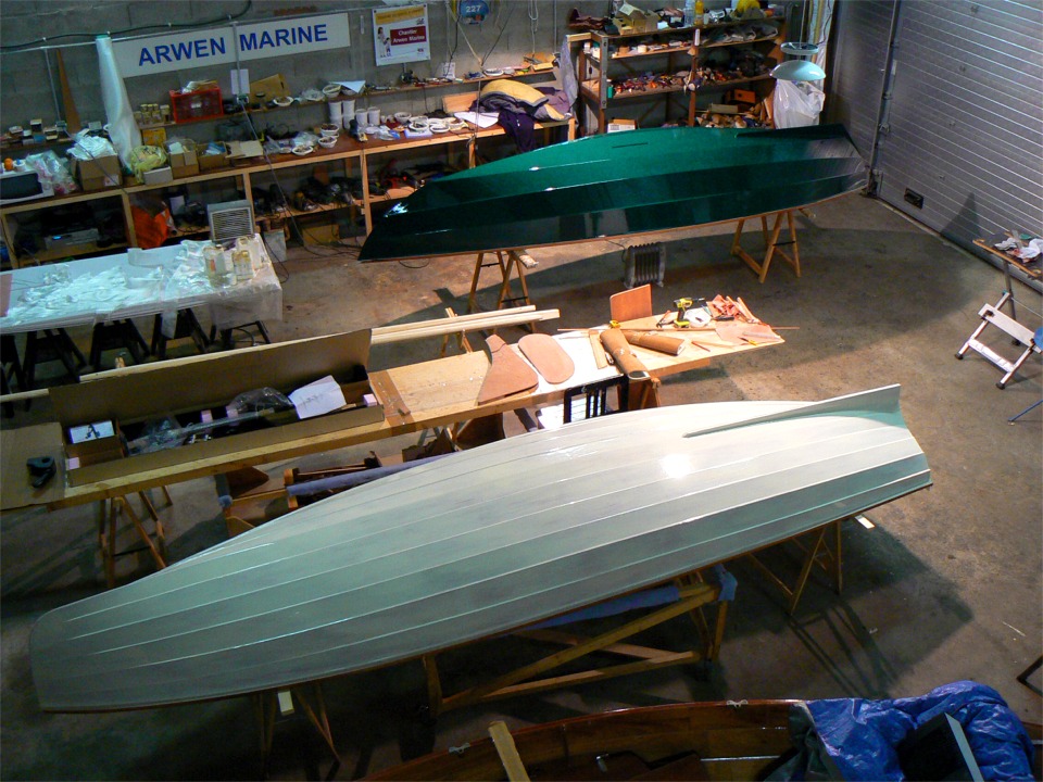 Je suis monté à l'échelle pour cette photo de fin de journée : au premier plan, la yole a reçu sa sous-couche blanc crème, et à l'arrière plan le Skerry a reçu sa seconde couche de finition vert "brouillard de jade" (les fabriquants de peinture sont des poêtes...) Sur la table entre les deux bateaux, c'est la boite du portant Piantedosi que je vais installer dans la yole. Juste à coté, on aperçoit le gouvernail et le safran du Skerry. 