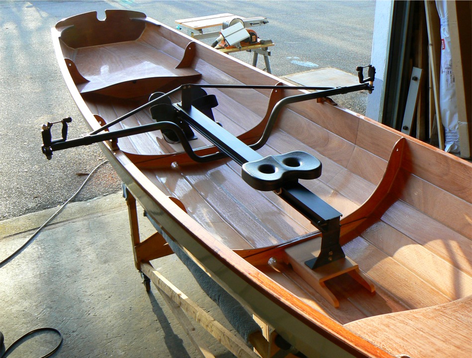 Une dernière vue depuis l'avant de la Yole de Chester pour profiter de cet (encore trop rare) soleil vespéral.... Le portant à siège coulissant Piantedosi montre l'élégance de sa fonctionalité : un gros profil en alu dont la section forme un "H" avec une double barre pivoté à 90° reçoit les six roues du siège dans un double rail de part et d'autre. La traverse est boulonnée sous le rail, les efforts sur les tolets étant repris par les haubans en tube qui reviennent sur le mâtereau entre les cale-pieds. L'ensemble pèse 8.5 kg