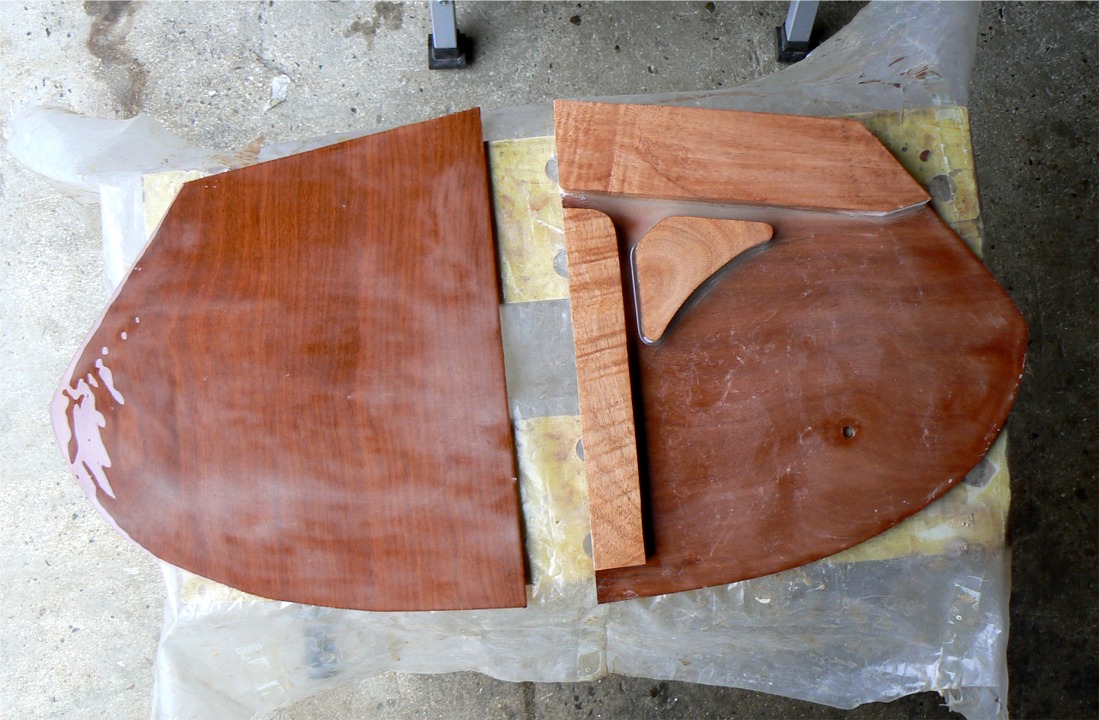 Suite de la construction du gouvernail pour le bateau de Ronan (voir d'autres images la semaine derni&egrave;re. Ici, la joue b&acirc;bord de la t&ecirc;te (&agrave; gauche sur l'image) est encoll&eacute;e de frais et je m'appr&ecirc;te &agrave; poser dessus la joue tribord, sur laquelle j'ai d&eacute;j&agrave; coll&eacute; les &eacute;l&eacute;ments d'&acirc;me. On voit que l'ensemble de la surface est satur&eacute; d'&eacute;poxy &eacute;paissie afin de prolonger le contreplaqu&eacute; des joues sur le long terme. 