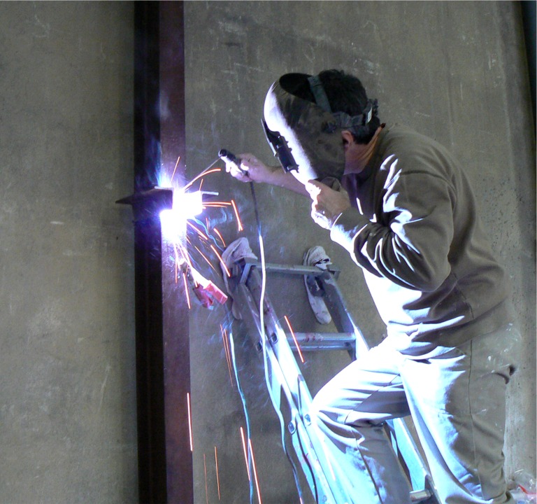 Voici Dominique occup&eacute; &agrave; souder les supports de la charpente de la mezzanine que nous construisons &agrave; l'atelier (rappelez-vous du tas de madriers et de bastaings de notre derni&egrave;re mise-&agrave;-jour). Comme cette image ne l'indique pas, Dominique fait chez Arwen Marine l'un des stages du cursus de son CAP d'Eb&eacute;nisterie. 