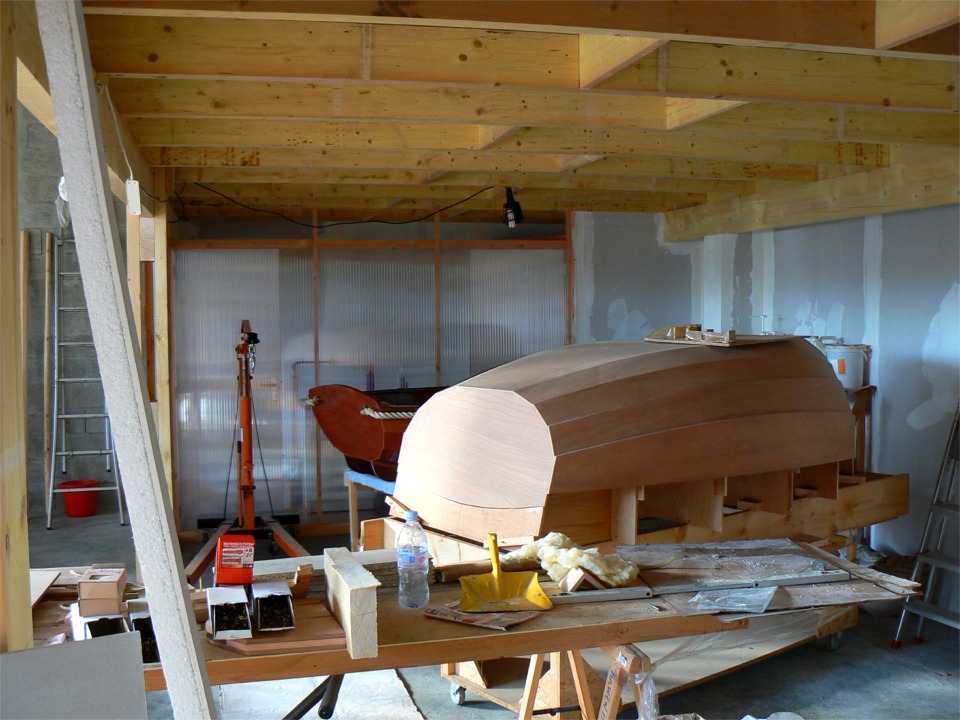 Encore une vue de la zone cuisine-toilettes, au fond, apr&egrave;s mise en place de la cloison qui les s&eacute;pare de "l'atelier couvert". Il ne reste plus qu'&agrave; fermer le haut de la cloison : on le fera soit en polycarbonate pour la lumi&egrave;re, soit en sandwich contreplaqu&eacute;-laine de verre, ce n'est pas encore d&eacute;cid&eacute;. Notez que le mur du fond a &eacute;t&eacute; couvert de BA13 afin d'obtenir une surface nette et d'isoler un peu ce mur int&eacute;rieur. Il reste encore &agrave; poser la laine de verre sous le plancher entre les bastaings, mais on verra &ccedil;a d'ici le d&eacute;but de l'hiver prochain. 