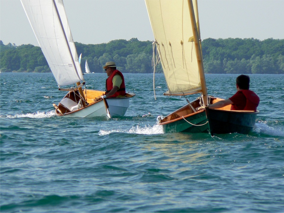 Dans les images du rassemblement de Skerry au Lac d'Orient, je vous avais parlé des bancs latéraux de Gérard : cette image montre clairement que Gérard, dans son Skerry blanc est assis nettement plus haut que Ronan, assis sur la sole dans le mien. Certes, le centre de gravité de Ronan est un peu plus bas et il a une meilleure vue sous la bôme (en se baissant un peu moins que Gérard), mais le couple de rappel de Gérard est un peu meilleur. Quant au confort, il n'y pas photo : Gérard n'a plus le fond de culotte humide ! 