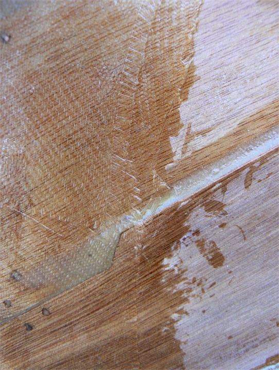 Vue de détail de la stratification de l'étrave juste sous le brion. L'étrave est à gauche de l'image. On aperçoit le recouvrement de la pièce de fibre du brion par dessus celle de l'étrave, qui elle-même vient recouvrir celle des bordés de fond. Notez la découpe du bordé qui facilite la tansition entre le franc-bord sur l'étrave et la superposition du clin. 