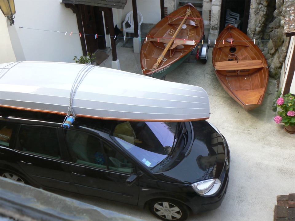 Je prends cette photo de ma cour encombrée de bateaux avant de partir livrer la Yole de Chester, déjà sur les barres de toit. Notez que le verre de la fenêtre déforme un peu l'image : on voit sur la grande version de cette image que le liston de la yole a l'air sinueux... A l'arrière-plan, c'est le Skerry sur la remorque, et le Doris 12 à droite. 