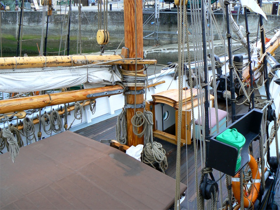 Le pied du grand mât du même ketch, avec plein de détails de gréement et d'armement, à commencer par le ratelier, à gauche sous la bôme et en finissant par le feu de route tribord, vert, à droite. 