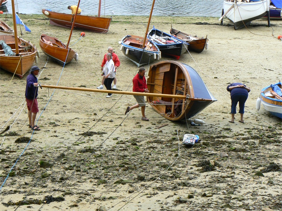 Un Ilur abattu en carène : sa dérive pivotante est coincée par des petits caillloux et l'équipage s'affaire à la débloquer. 