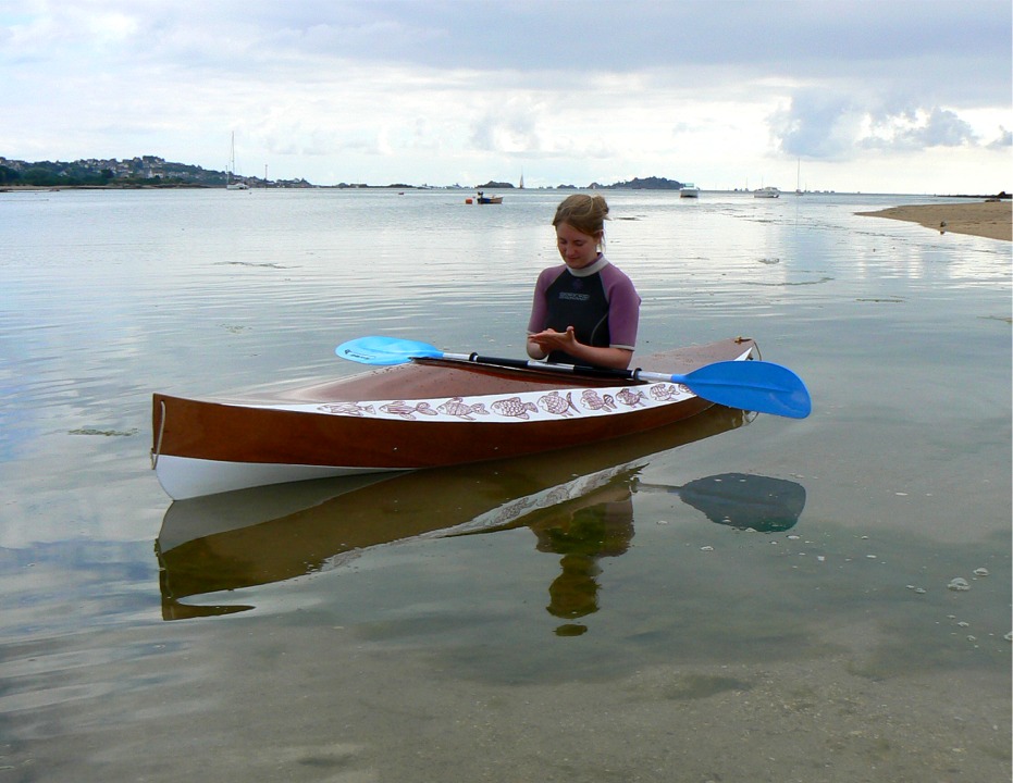 Juliette se recueille brièvement mais intensément avant d'entamer cette traversée inaugurale (en fait, elle tente de se rappeler à qui appartient ce numéro de portable dans sa main gauche). Le Wood Duck flotte bien dans ses lignes, le brion bien arrondi émerge à peine au bas de l'étrave verticale, et la carène est bien posée sur la largeur généreuse des deux panneaux de fond en V très ouvert.