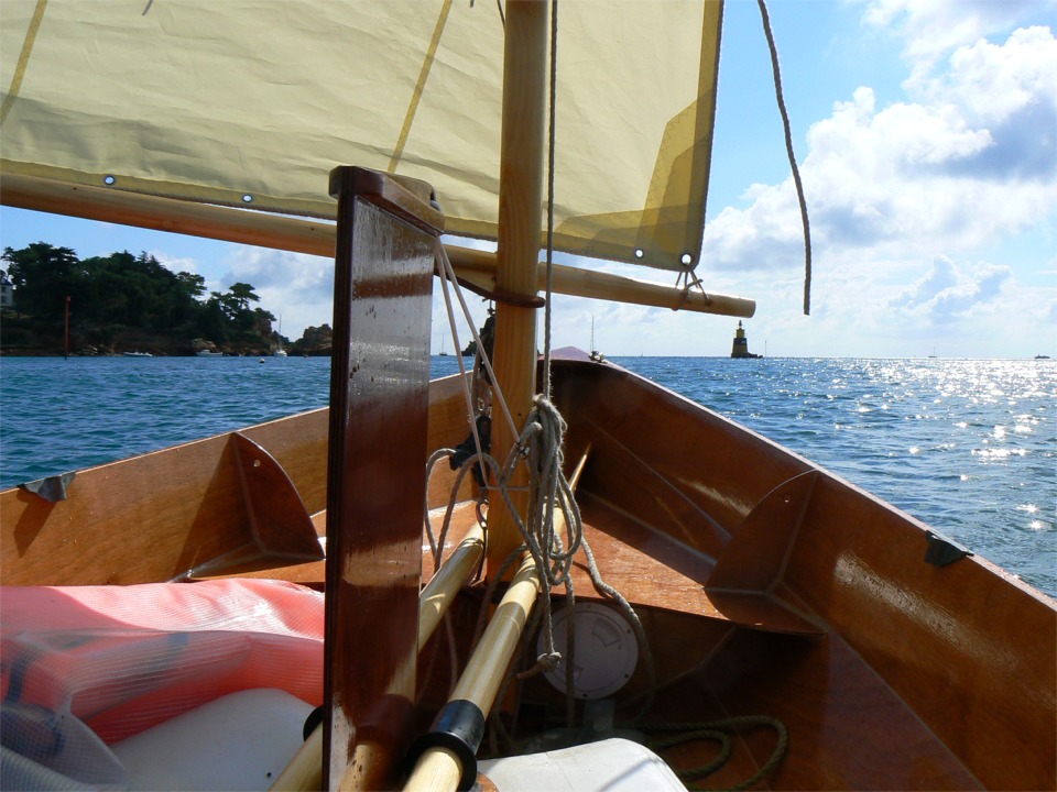 Encore quelques instants et le soleil sort des nuages pour éclairer ce paysage paradisiaque. J'ai totalement relevé ma dérive pour le vent arrière. Le tendeur blanc qui passe autour du mât la tient en position haute (ou basse) en la coinçant en biais dans son puits. 