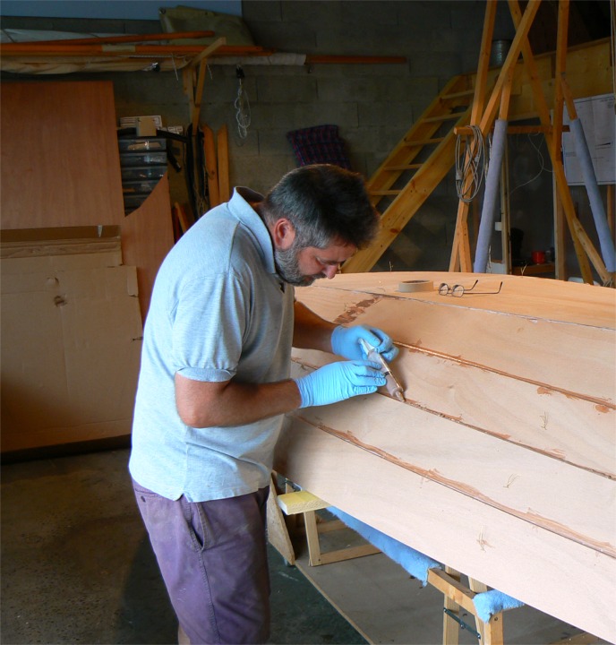 Apr&egrave;s durcissement de ce premier collage, j'ai coup&eacute; et extrait les sutures entre les bord&eacute;s (et conserv&eacute; celles de l'&eacute;trave, du tableau et des membrures, dont je ferai bient&ocirc;t les joints-cong&eacute;s par l'int&eacute;rieur). Sur cette image, je compl&egrave;te les joints ext&eacute;rieurs : une partie de l'&eacute;poxy a &eacute;t&eacute; "bue" par le bois, et il faut donc compl&eacute;ter le remplissage des joints. Je les lisse ensuite en arc de cercle concave pour l'esth&eacute;tique et l'hydrodynamisme. 