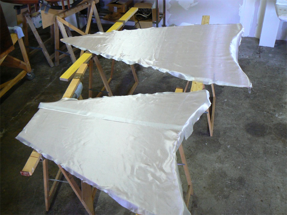 Je stratifie un tissu l&eacute;ger sur les dessus des caissons. Il s'agit de chutes du tissu du pontage d'un kayak (rien ne se perd) et j'ai du juxtaposer deux pi&egrave;ces sur le dessus du caisson arri&egrave;re, au premier plan. C'est la face sup&eacute;rieure des dessus de caisson qui sera stratifi&eacute;e, afin de la durcir en vue des impacts qu'elle devra subir. Les deux pi&egrave;ces seront rigidifi&eacute;es par des barrots coll&eacute;s sur leur face inf&eacute;rieure car elles sont tr&egrave;s peu soutenues pour des pi&egrave;ces de cette surface.