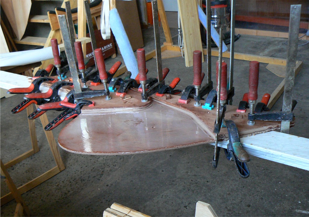 Ce meeting de pinces et de presses est en fait le collage des deux pi&egrave;ces de l'&acirc;me du gouvernail du Doris 17 sur sa joue b&acirc;bord. Je fais le collage sur ma r&egrave;gle en aluminium afin de m'assurer que mon gouvernail sera bien rectiligne. L'&acirc;me est en deux pi&egrave;ces afin de laisser un "canal" libre entre les deux pi&egrave;ces, pour y passer les manoeuvres de commande de pivotement du safran. 